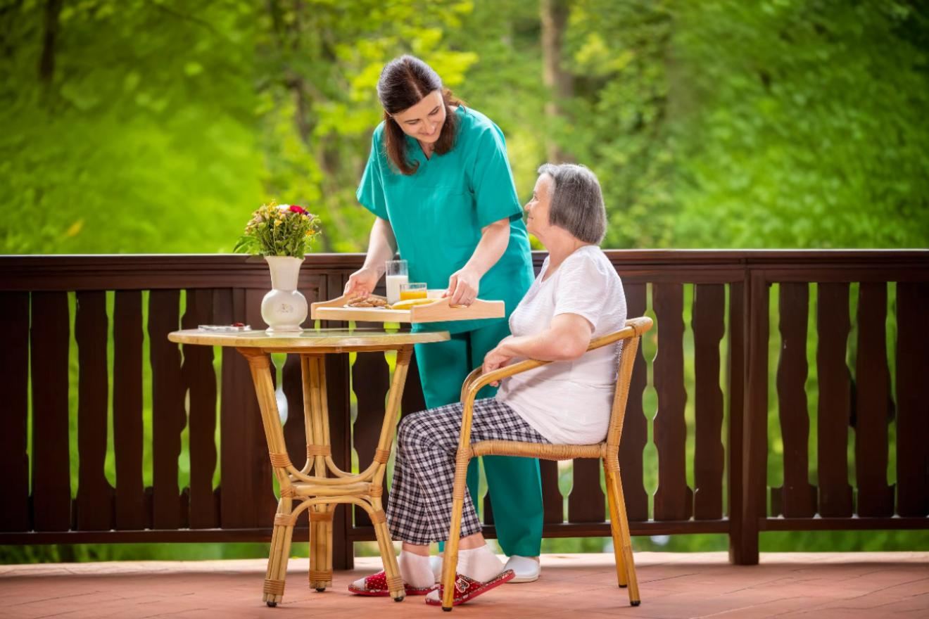 An older adult and family caregiver smiling together while looking at the Maia app on a phone